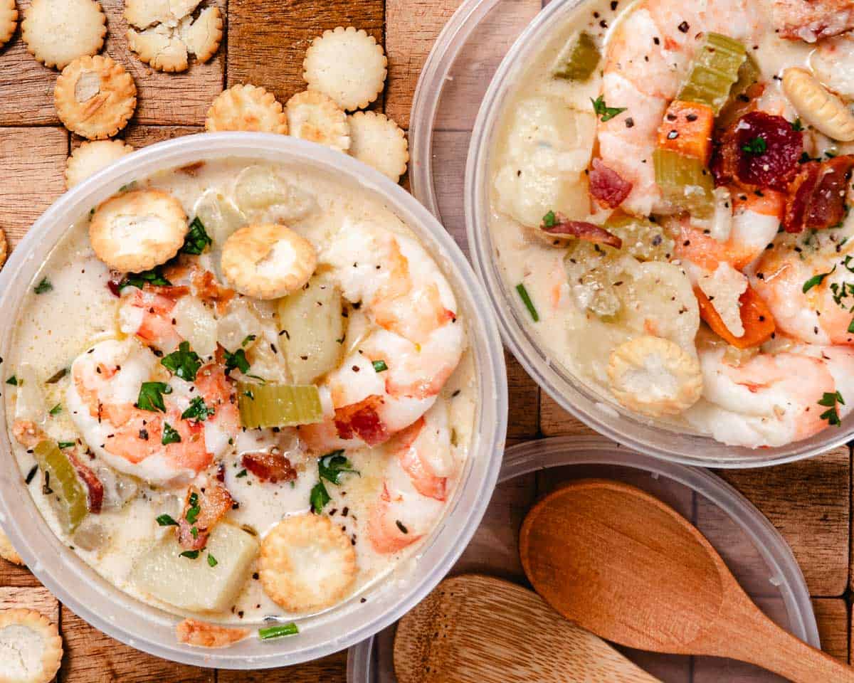 Leftover shrimp chowder with bacon, potatoes, vegetables, parsley, and oyster crackers in plastic storage containers.