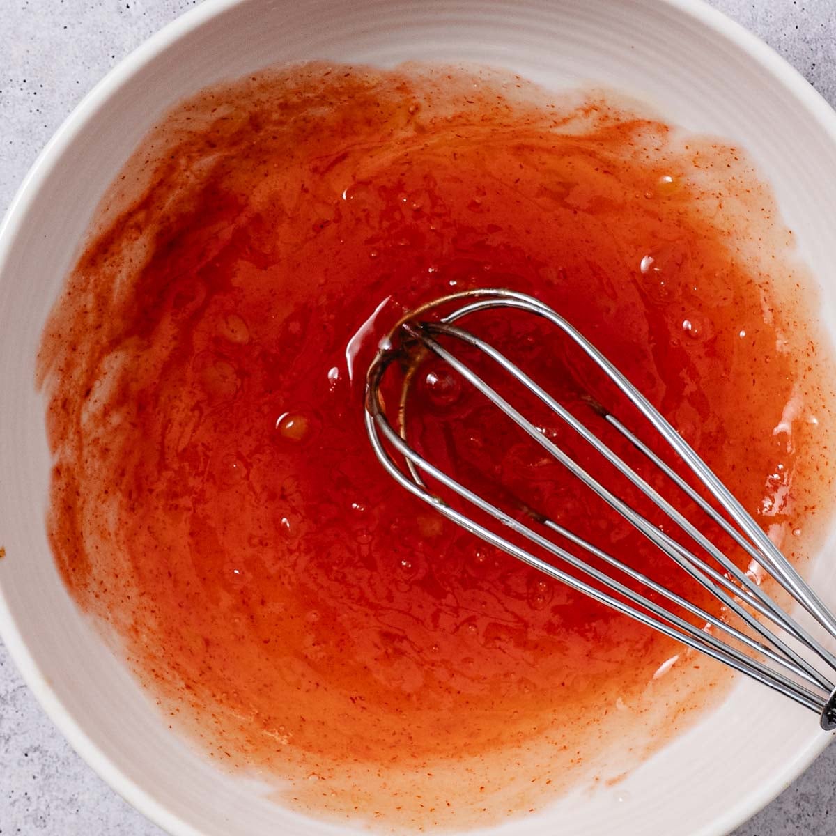 Whisking sweet chili lime sauce in a bowl.