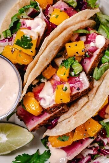 Blackened tuna tacos with mango salsa, lettuce, and spicy mayo on corn tortillas