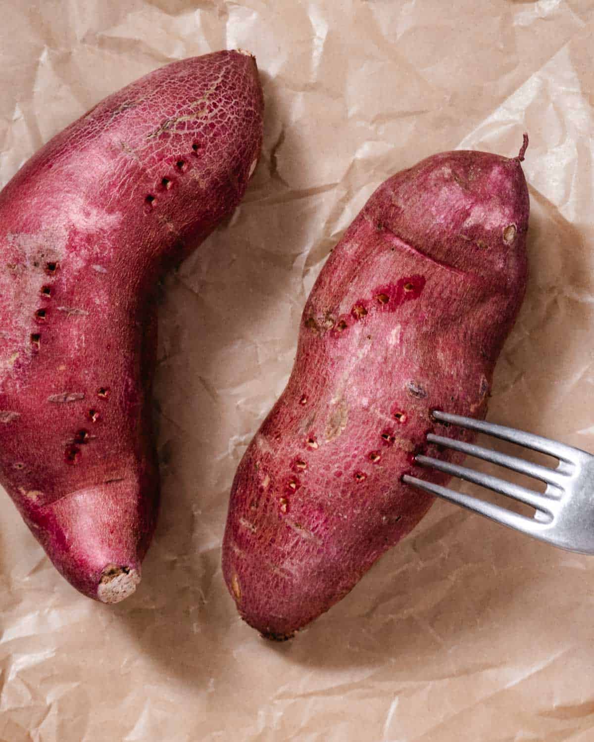 Pricking Japanese sweet potatoes with a fork before baking