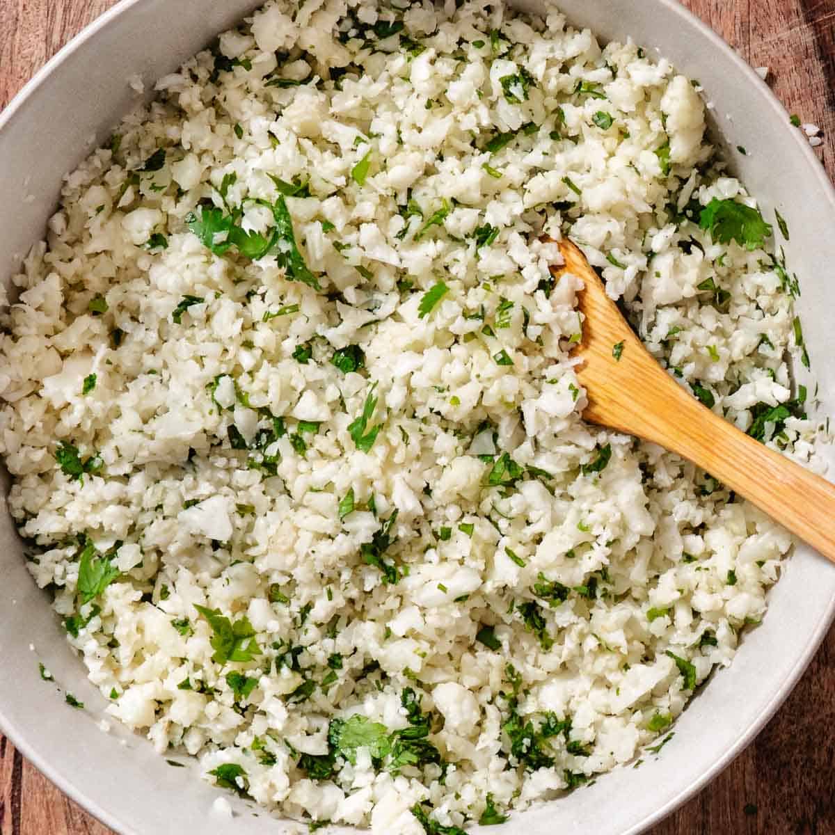 Cilantro lime cauliflower rice cooking in a skillet with chopped fresh cilantro stirred throughout.