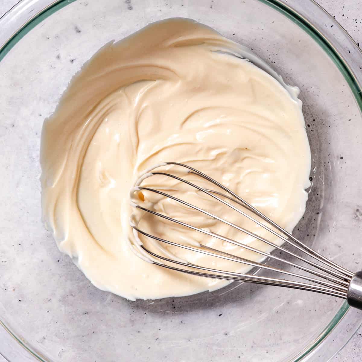 Mixing turkey salad dressing in a bowl.