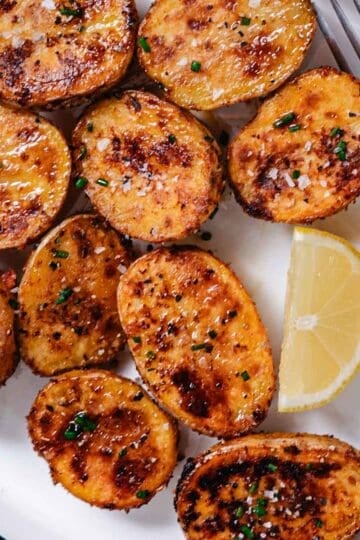 Crispy roasted baby potatoes seasoned with herbs on a white serving plate