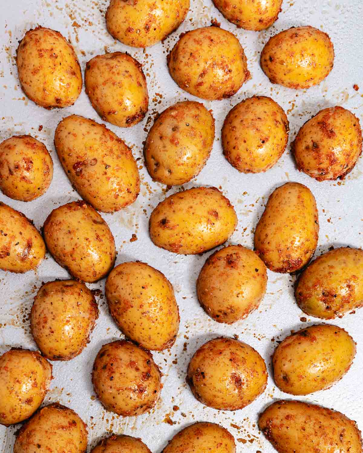 Seasoned baby potatoes arranged cut side down on a baking sheet