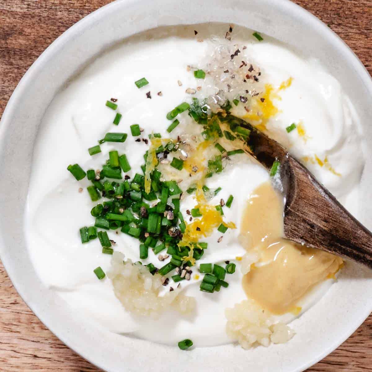 Ingredients for lemon chive sour cream dip including sour cream, chives, Dijon mustard, garlic, lemon zest, black pepper, and lemon juice.