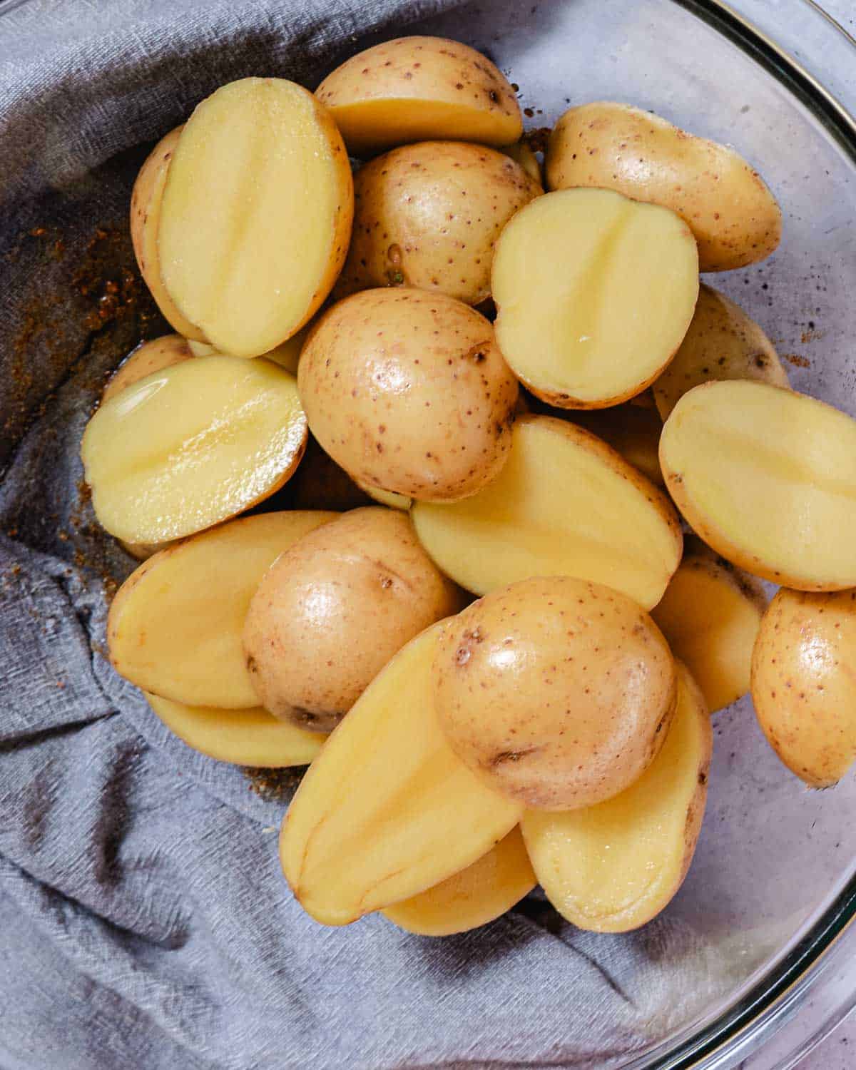 Halved baby yellow potatoes in a glass mixing bowl