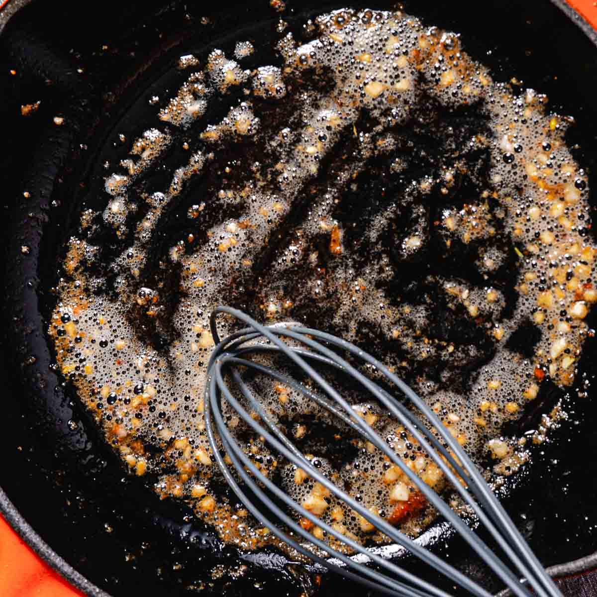 Garlic butter and minced garlic bubbling in a skillet while making the pan sauce for pan seared coho salmon.