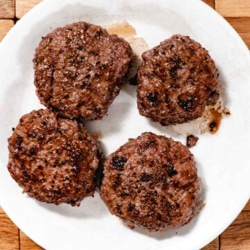 four burgers resting on a plate after cooking