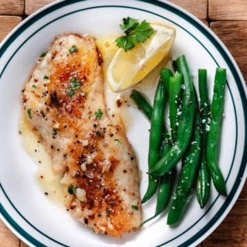 Blackbelly rosefish fillet browned in a skillet and served with lemon butter sauce and green beans.