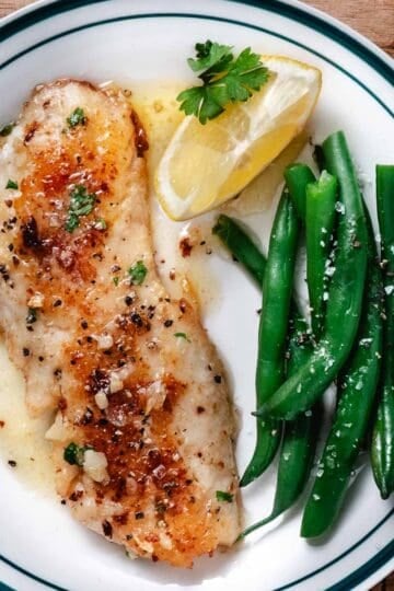Blackbelly rosefish fillet browned in a skillet and served with lemon butter sauce and green beans.