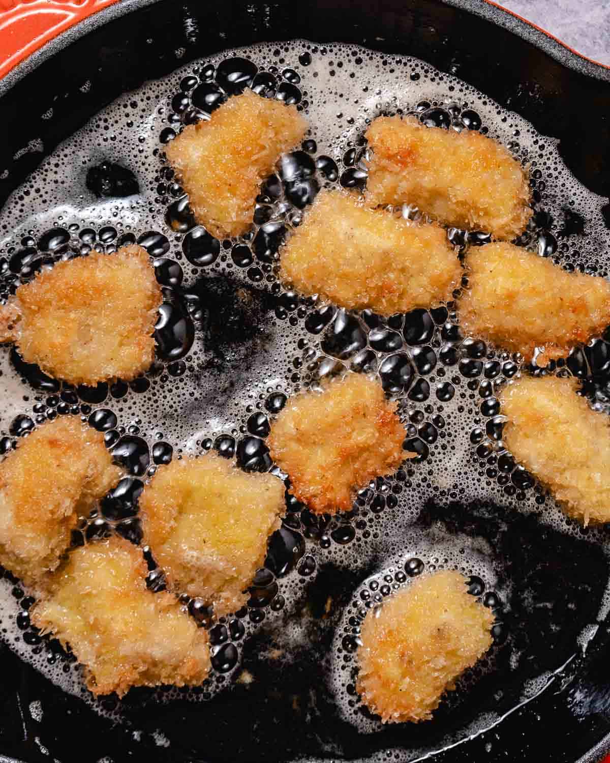 Panko-coated mahi mahi bites frying until golden and crispy in a skillet.
