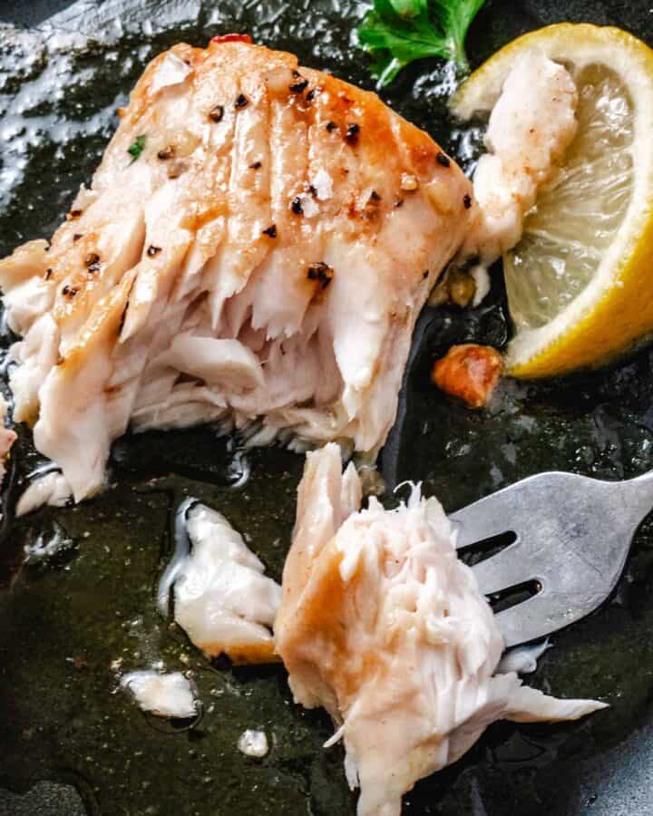 Flaky pan-seared mahi mahi with garlic butter, lemon, and a fork lifting a piece of fish.