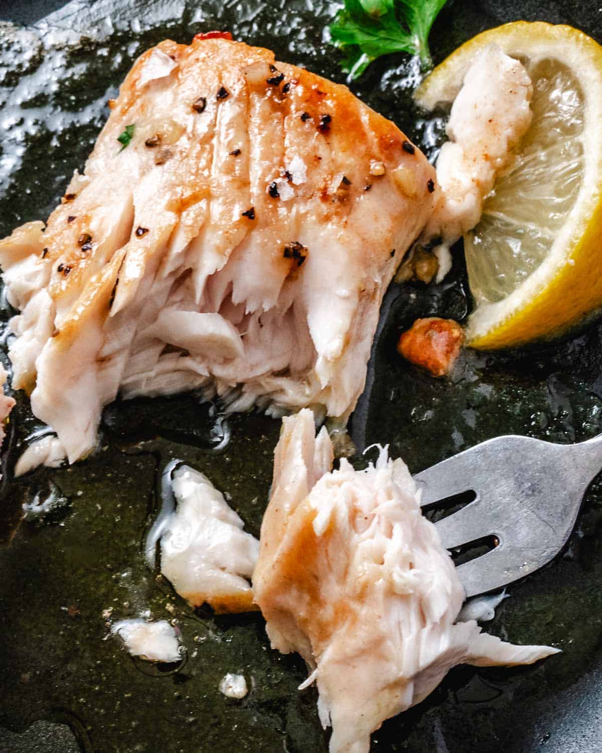 Flaky pan-seared mahi mahi with garlic butter, lemon, and a fork lifting a piece of fish.