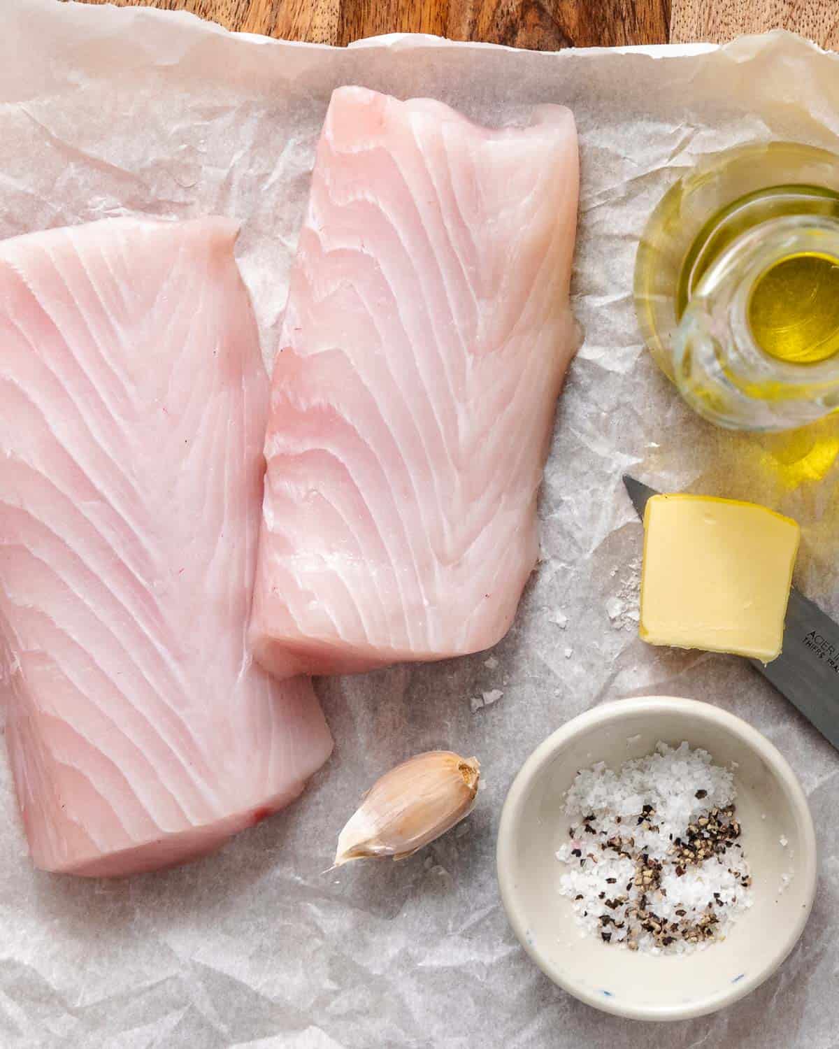 Pan-seared fresh mahi mahi fillet with garlic butter and parsley on parchment paper.