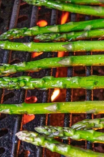 Grilling asparagus spears on gas grill.