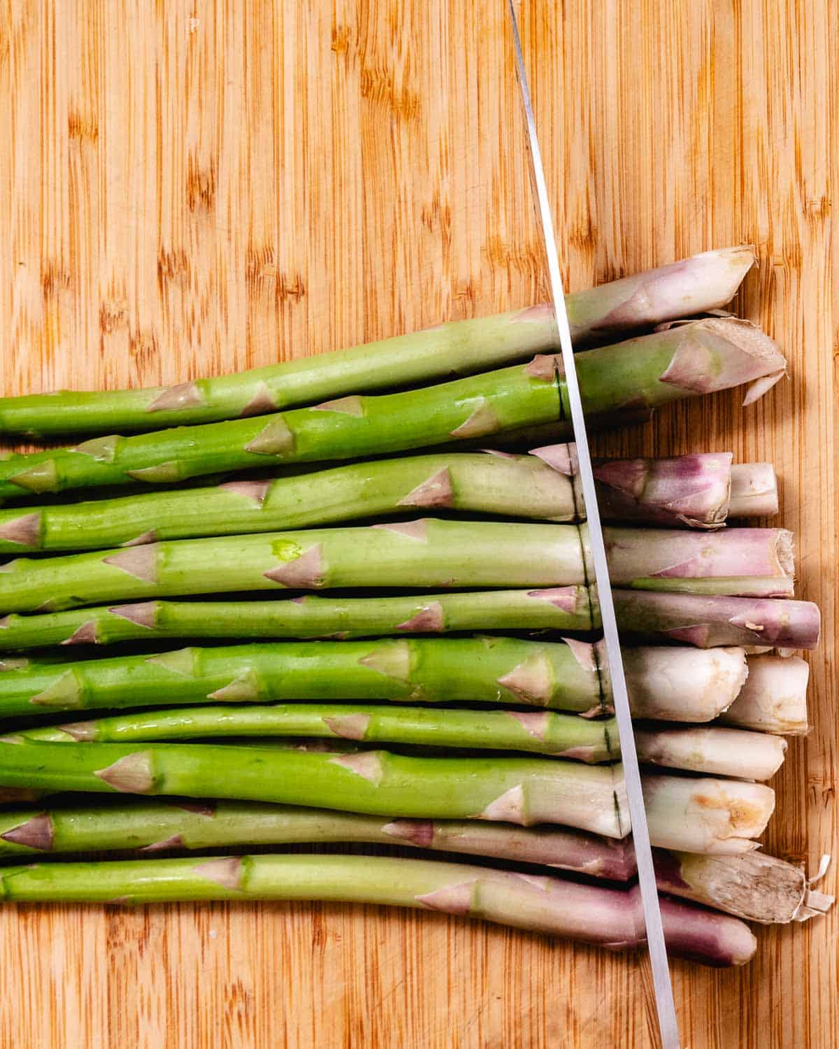 Scoring asparagus with a knife before snapping off the ends.