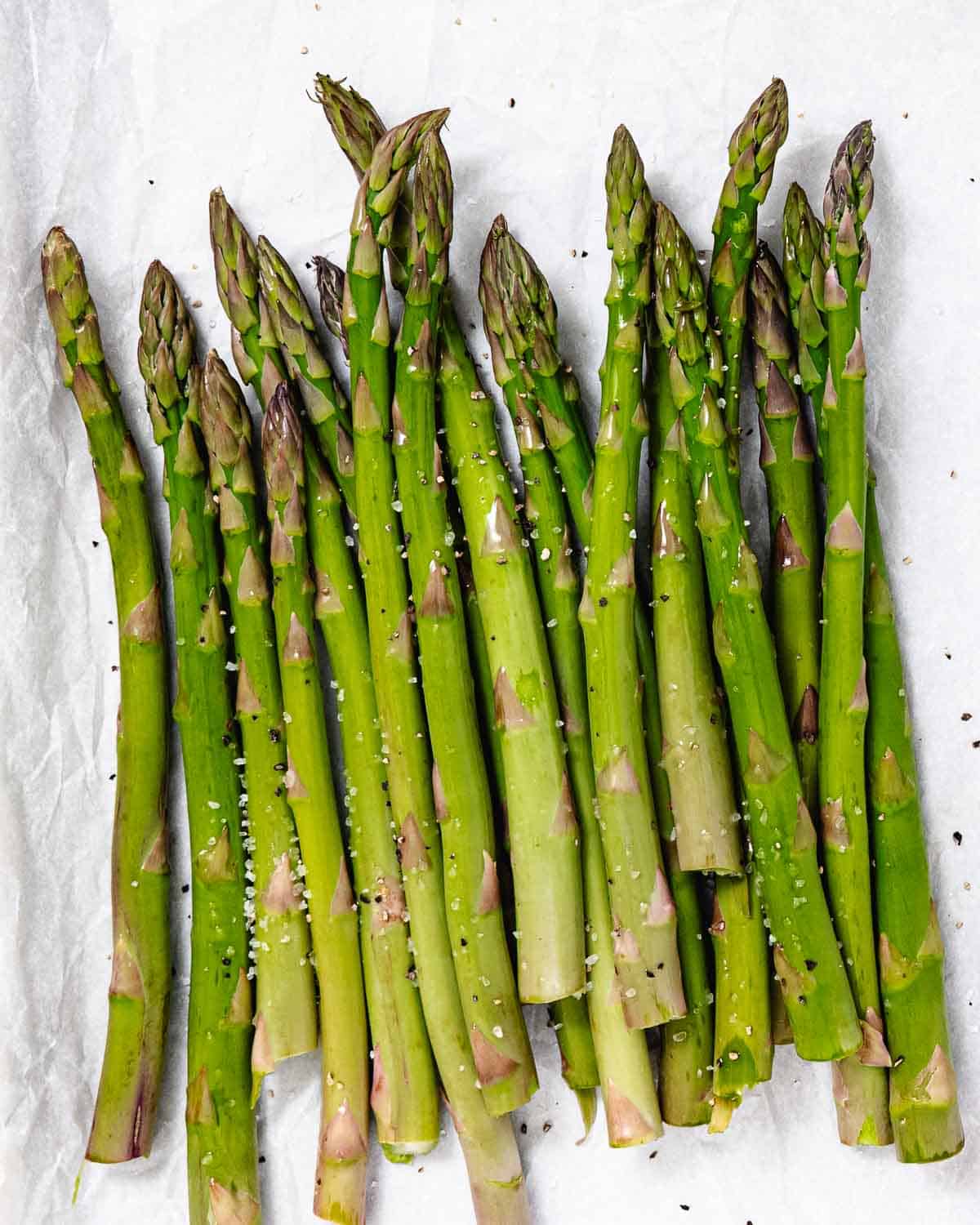 Seasoning asparagus before grilling.
