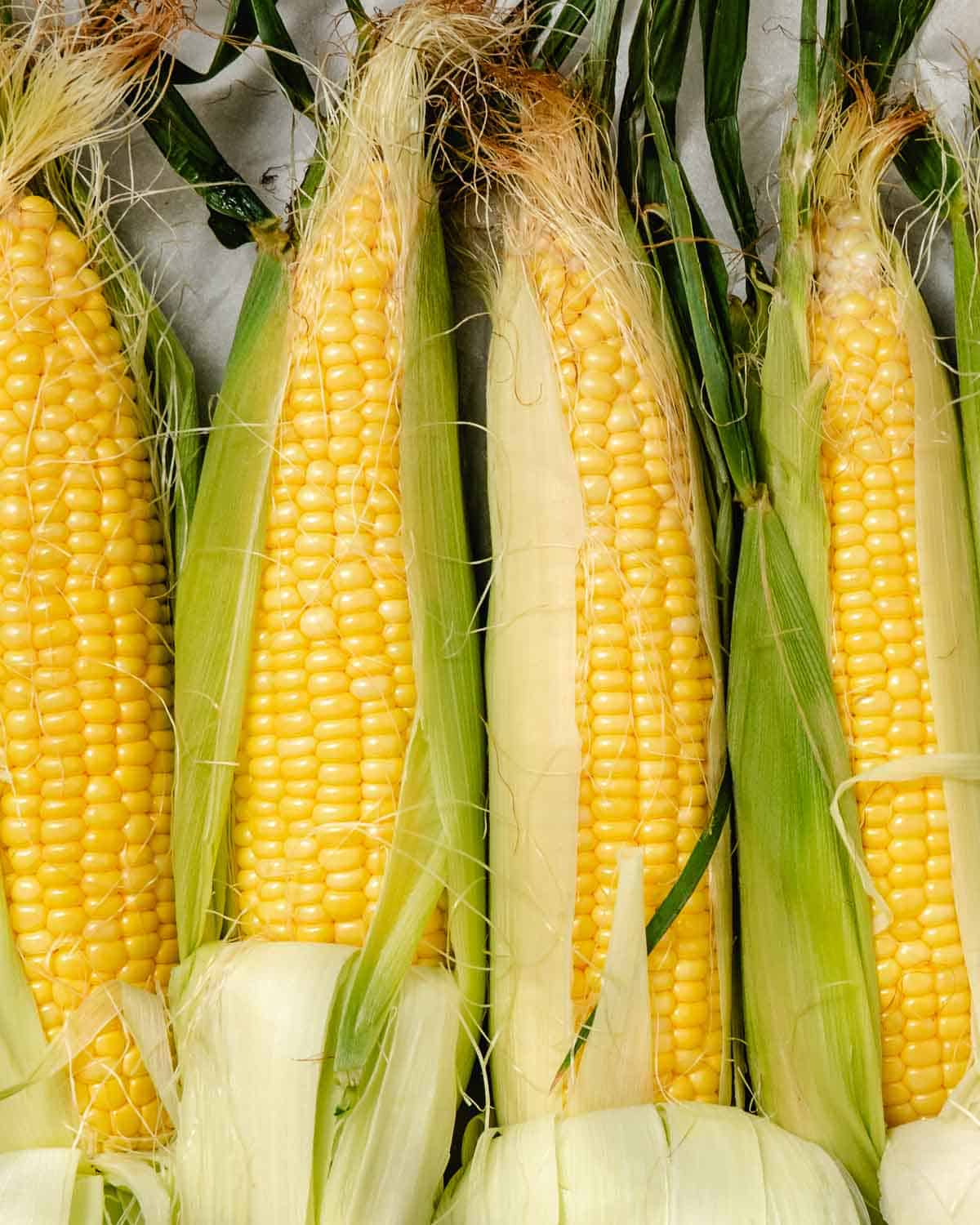 Grilled corn on the cob with Old Bay seasoning and charred lime halves.