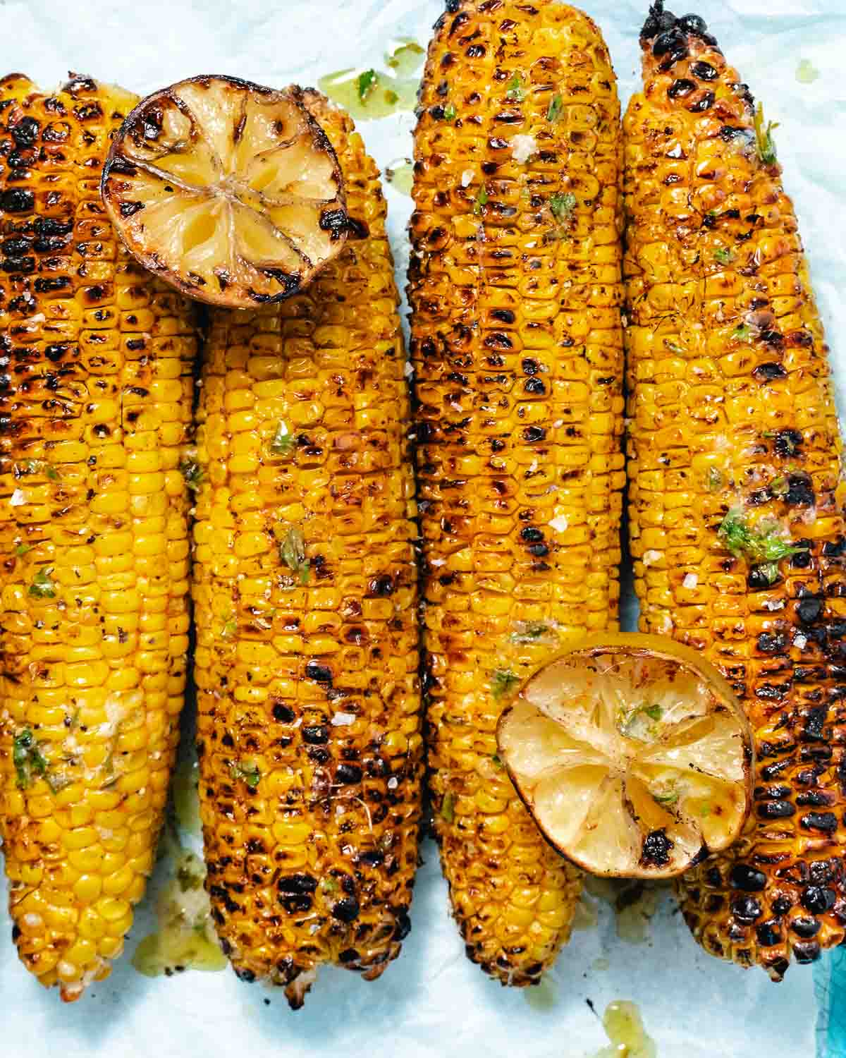 Grilled corn on the cob with Old Bay seasoning, charred limes, and lime butter sauce.