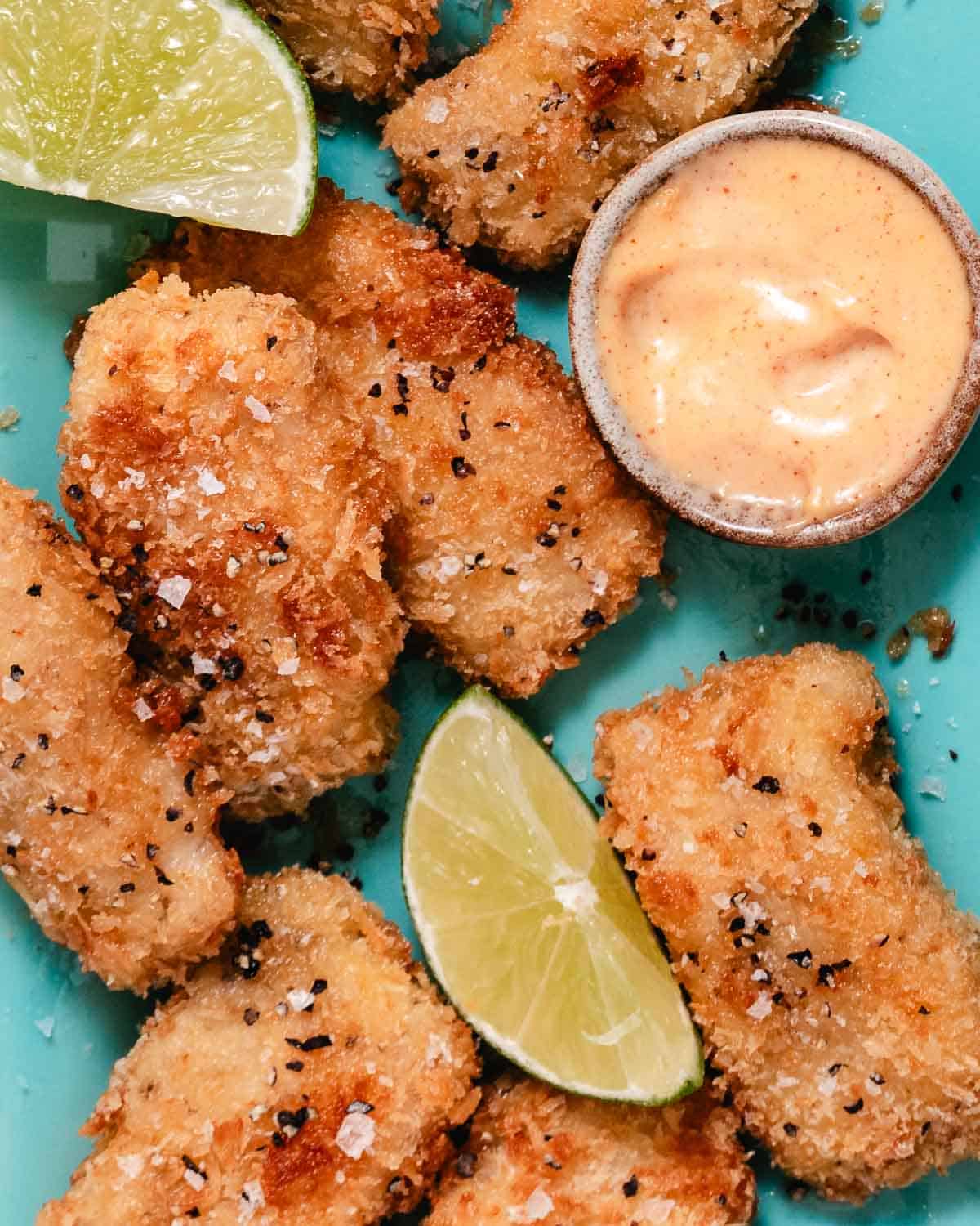 Crispy mahi mahi bites with lime wedges and creamy yum yum sauce.