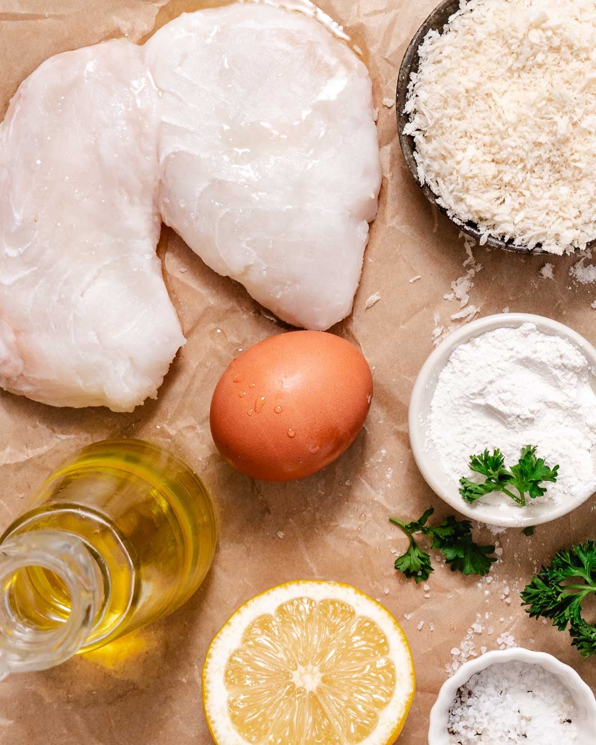 Raw halibut fillets with panko breadcrumbs, flour, egg, oil, salt, pepper, lemon, and parsley.