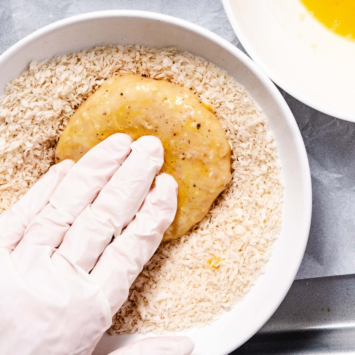 Pressing halibut into panko bread crumbs so it sticks.