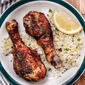 Crispy air fryer chicken drumsticks served with cauliflower rice and tomato salad.