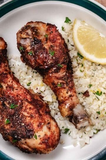 Crispy air fryer chicken drumsticks served with cauliflower rice and tomato salad.