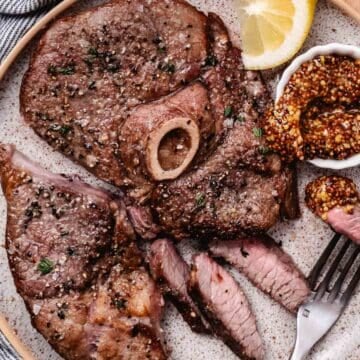 Air fryer lamb leg steak sliced and served with whole-grain mustard and lemon.