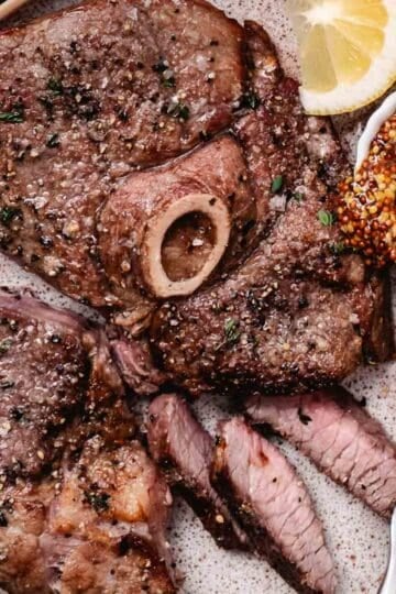 Air fryer lamb leg steak sliced and served with whole-grain mustard and lemon.