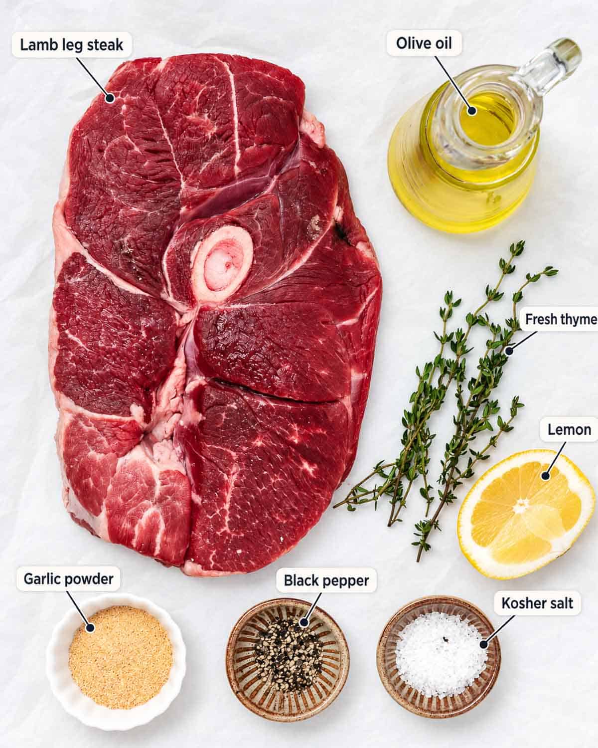 Air fryer lamb steak ingredients: lamb leg steak, olive oil, fresh thyme, lemon, garlic powder, black pepper, and kosher salt.