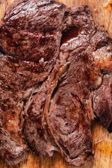Sliced pan-seared chuck steak on a wooden cutting board.