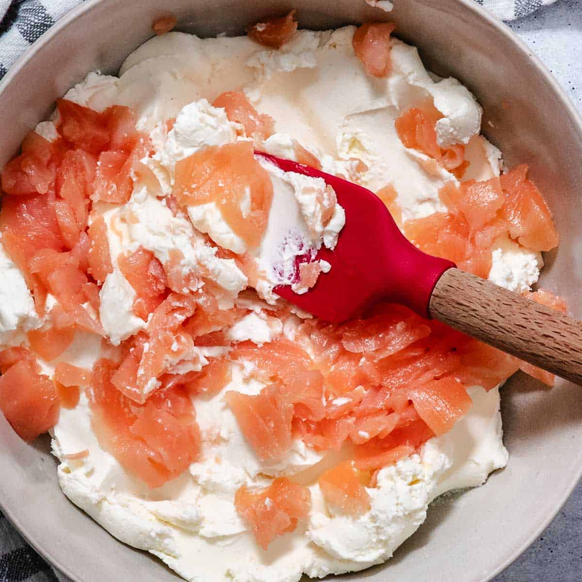 Smoked salmon and cream cheese in a mixing bowl before stirring.