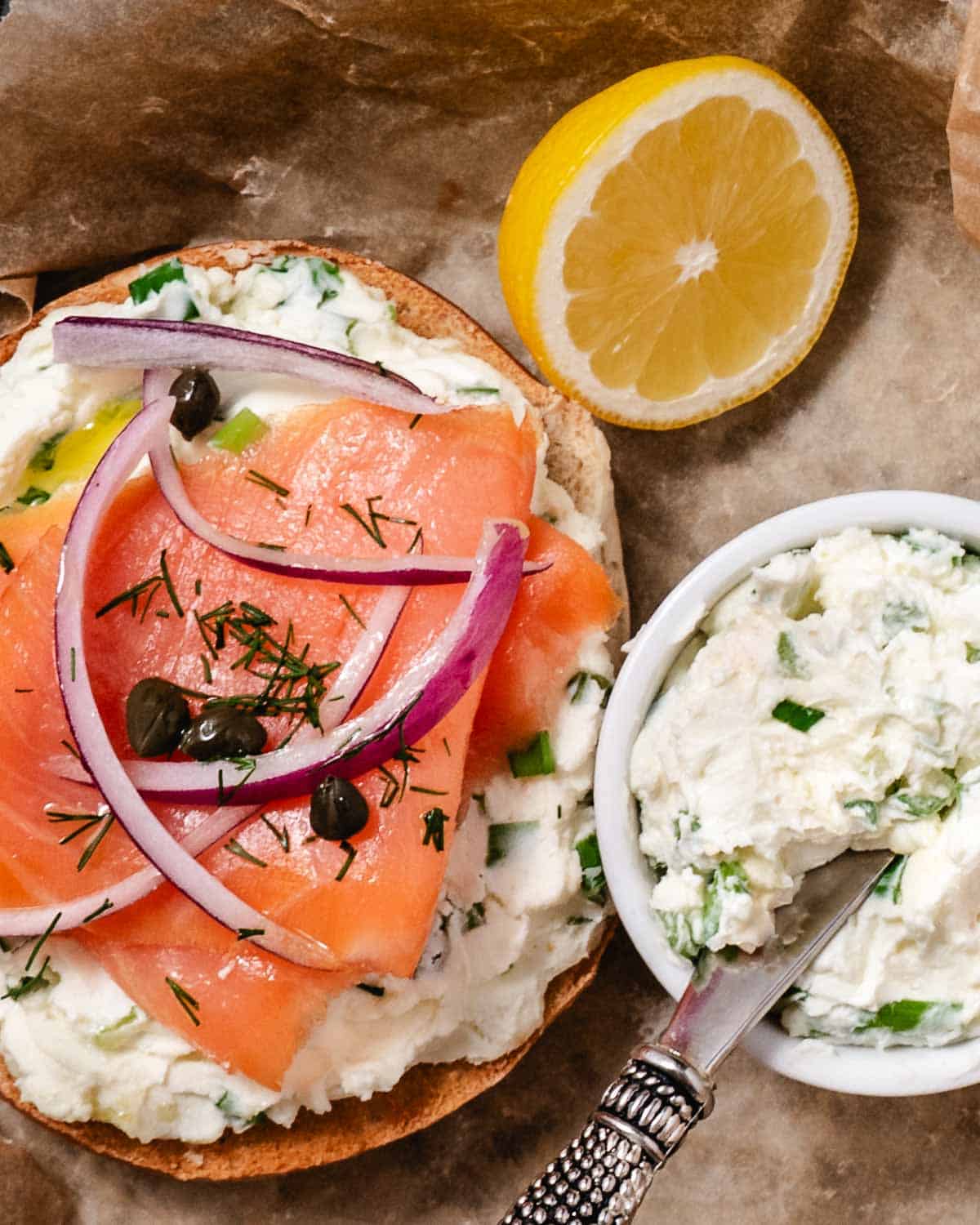 Scallion cream cheese with sliced salmon, onions, and capers on a bagel.