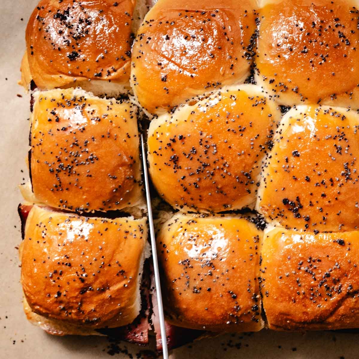Baked ham and cheese sliders cut into individual sandwiches.