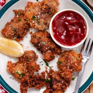 Fried chicken livers topped with chopped parsley and flaky salt, served with lemon and red dipping sauce.