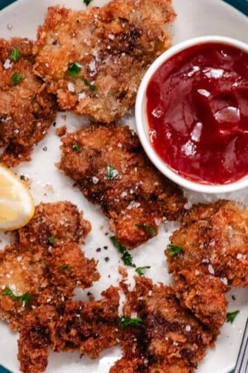 Fried chicken livers topped with chopped parsley and flaky salt, served with lemon and red dipping sauce.
