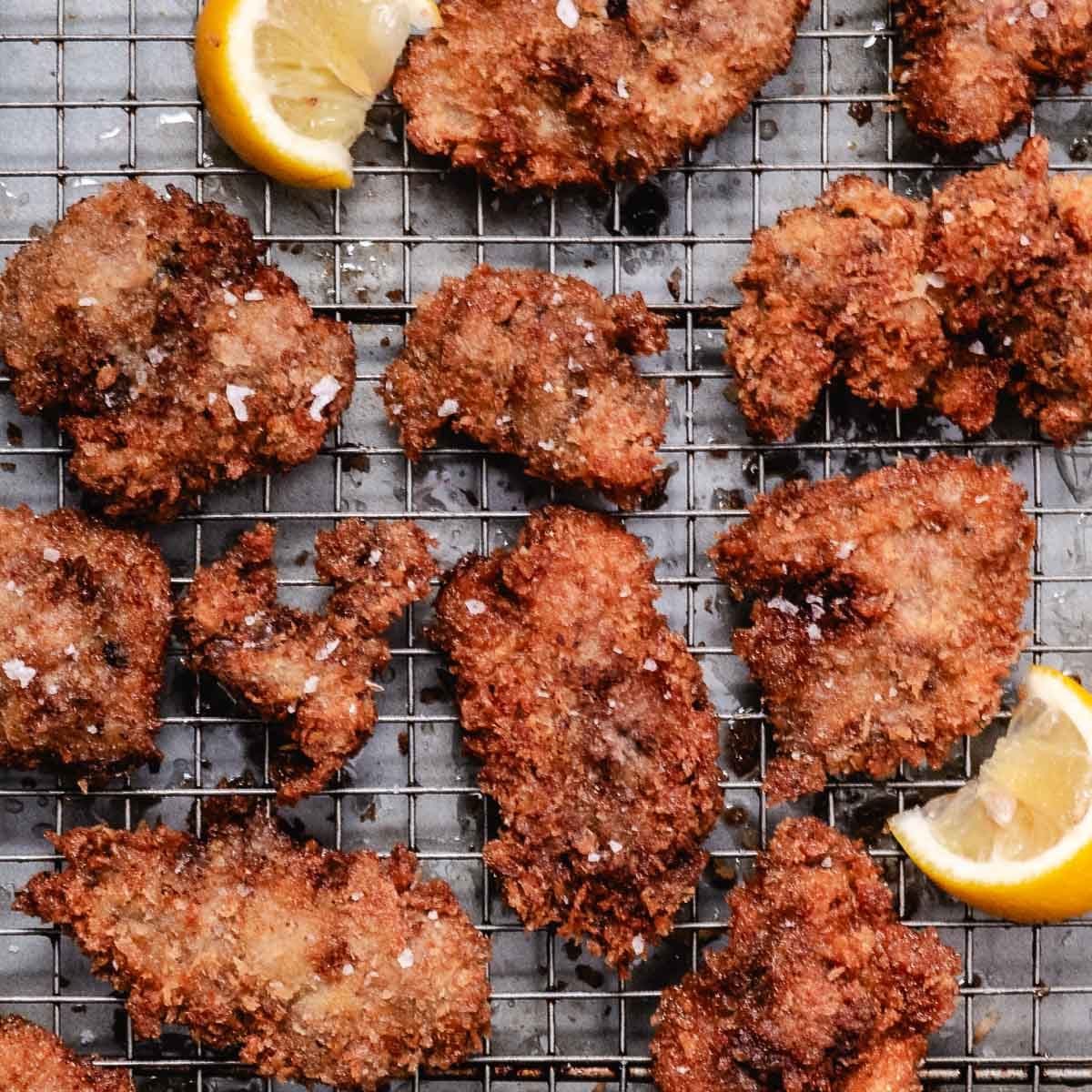 Panko-crusted fried chicken livers sprinkled with flaky salt, draining on a wire rack with lemon wedges.