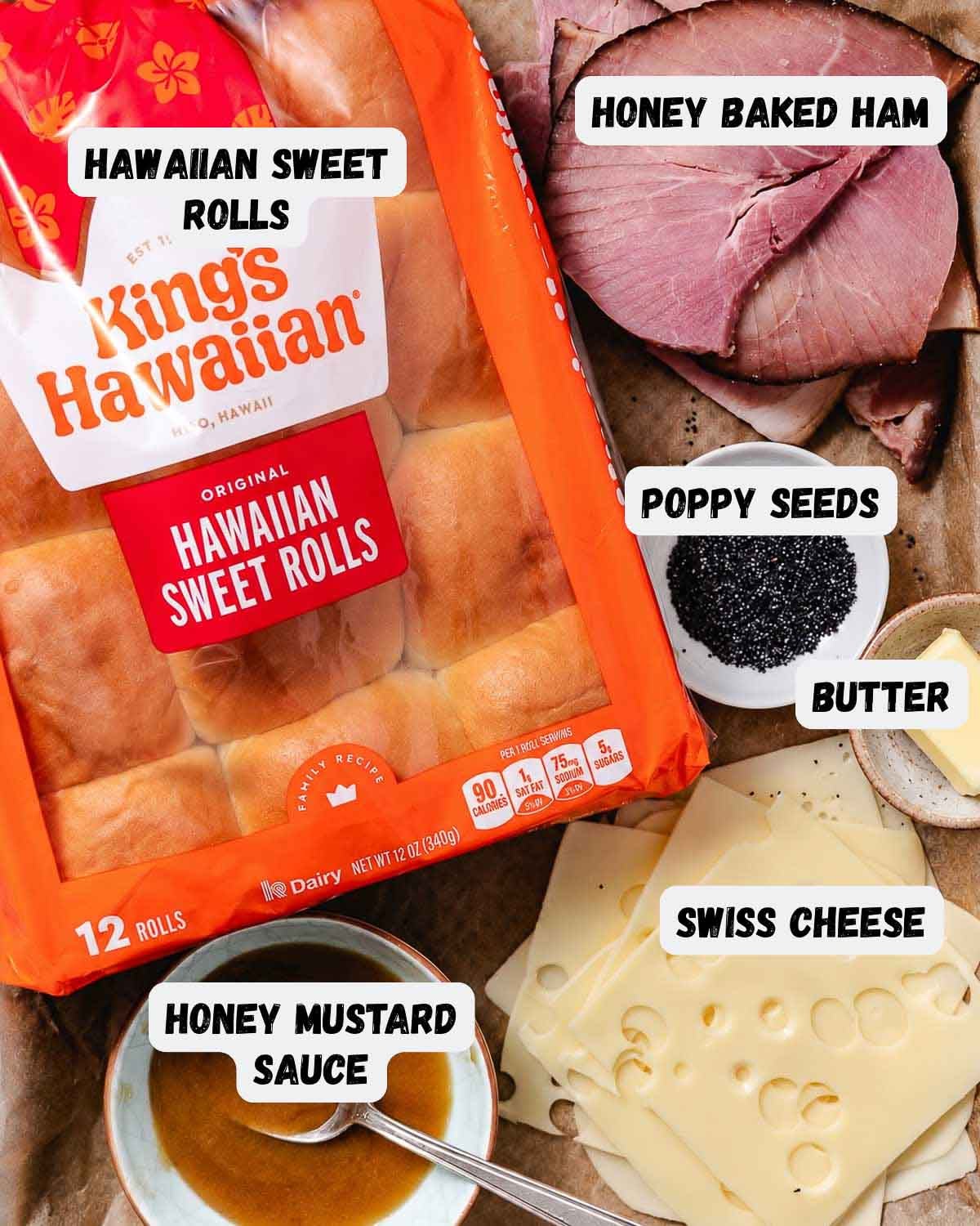 Ingredients for honey baked ham and cheese sliders: King's Hawaiian sweet rolls, sliced honey baked ham, Swiss cheese, honey mustard sauce, butter, and poppy seeds.