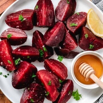 Steamed beet wedges topped with chopped parsley and salt in a white bowl.