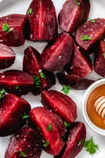 Steamed beet wedges topped with chopped parsley and salt in a white bowl.