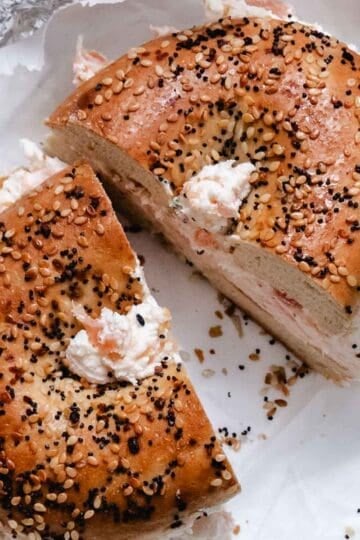 Smoked salmon cream cheese on an everything bagel cut into two halves.