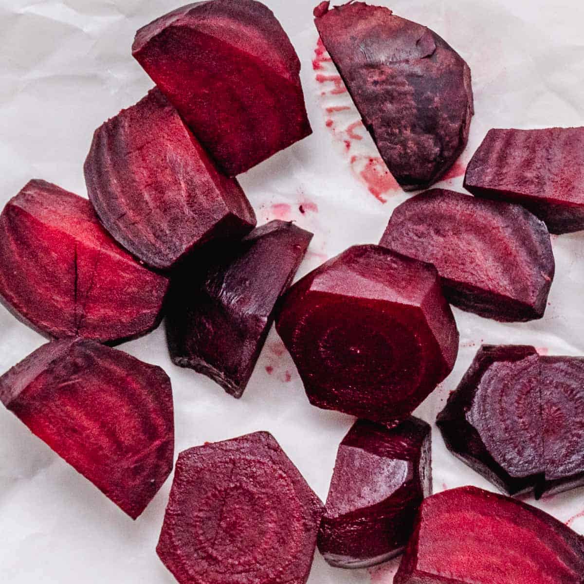 Cooked red beets on white parchment paper.